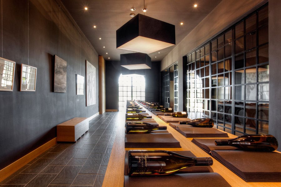 table from wood barells with wine bottles in the background of paintings on the wall of 'Domaine Skouras'